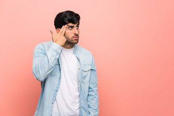 Obraz premium Young man over pink wall with problems making suicide gesture