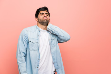 Young man over pink wall with neckache