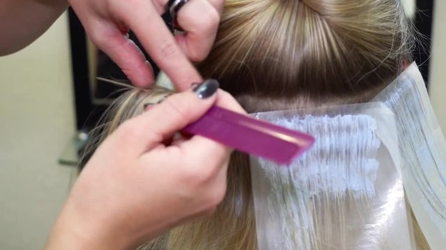 Hairdresser cutting long hair with the help of hairdressing scissors in a beauty salon. Closeup of hairdresser making haircut to woman with scissors in hair salon. haircut process.