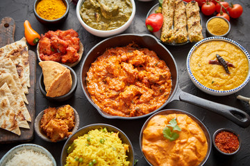 Various Indian dishes on a table. Spicy chicken Tikka Masala in iron pan
