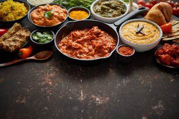 Assortment of various kinds of Indian cousine on dark rusty table