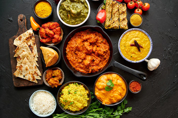 Assortment of various kinds of Indian cousine on dark rusty table