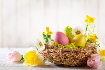 Easter composition with Easter eggs in nest, spring flowers and branches of pussy willows.