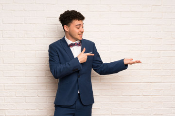 Man in suit and bow tie holding copyspace imaginary on the palm to insert an ad