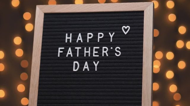 Black letter board with HAPPY FATHER'S DAY title on it. Camera rotating around the sign showing the beautiful bokeh balls in the background.