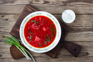 Traditional  ukrainian vegetarian beet red soup - borscht with sour cream on wooden background. Top view.