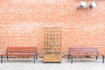 City park background. Wooden benches, wooden pergola with flowerbed near red brick wall