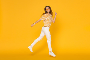 Fototapeta na wymiar Cheerful positive girl jumping in the air, isolated on yellow background