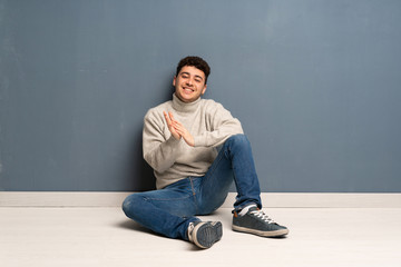 Young man sitting on the floor applauding after presentation in a conference