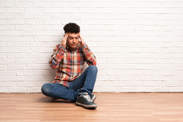 Fototapeta na wymiar Young man sitting on the floor with headache