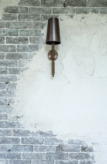 Luxury lamp hanging on brick and plaster wall.