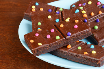 closeup chocolate fudge brownies with candy pieces on blue plate