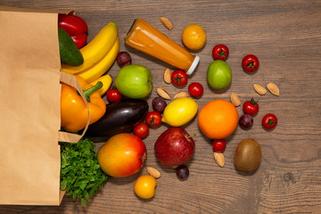 Full paper bag of different health food on wooden background, close up. Grocery shopping concept, top view.