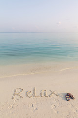  .World RELAX written on sand early in the morning on cristal clean beach of Maldives.