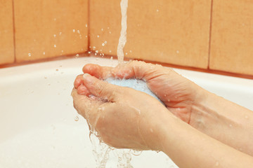 Fototapeta premium Female hands with soap under the water in the bathroom