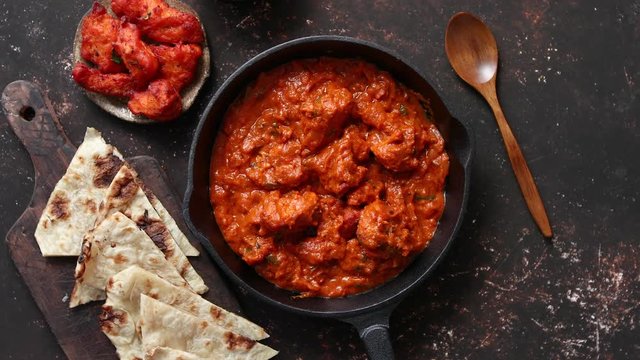 Traditional Indian chicken tikka masala spicy curry meat food in cast iron pan