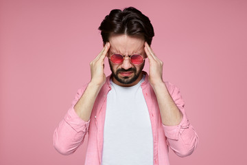 Upset unhappy caucasian man squeezing head with hands, writhing in pain, suffering from headache after he spent sleepless night preparing for exams. People, stress, tension and migraine.