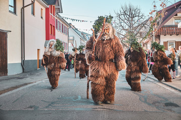 Haired wild man with hiking stick. Carnival party in southern Germany - Black Forest.