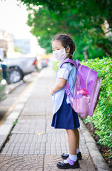 thai girl student with backpack wear a mask against PM 2.5 air pollution before going to school