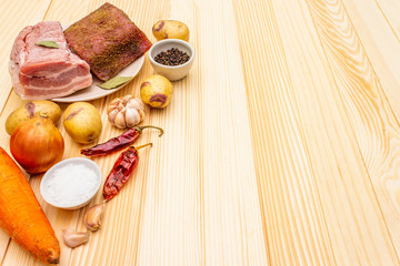Ingredients for meat stew with potatoes and vegetables. Raw pork fillet, brisket, spices on a stone background, copy space.