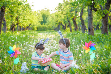 children having fun and playing with easter eggs. two cheerful boys sit on the lawn after Easter...