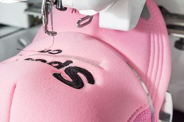 Close up picture of pink cap and embroidery machine