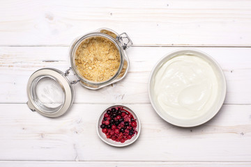 Prepare shortbread crumbs, cottage cream and berries. recipe step by step no bake cheesecake flatlay on white wood