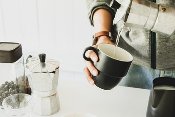 Hand hold Mokapot coffee pouring in cup with