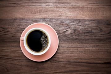 Hot coffee of cup trendy color of the year 2019 living coral. On wooden background