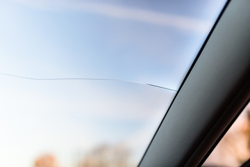 A long rupture of the windshield in the car, from the cars pillar to the center. Blue sky in the background