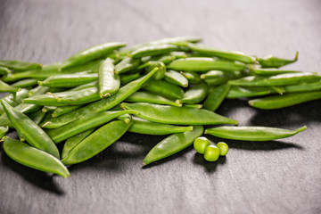 Lot of whole young green sugar snap pea on grey stone