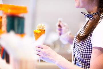 Young girl behind the counter holding an ice cream