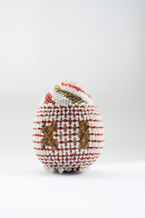 One Easter egg made from beads on a white background