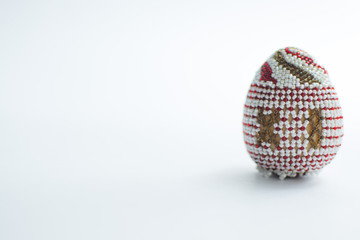 One Easter egg made from beads on a white background