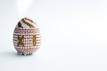 One Easter egg made from beads on a white background