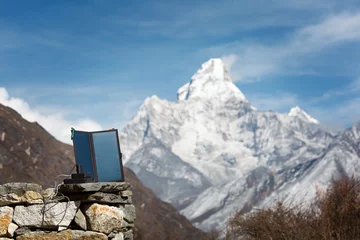 Papier Peint photo Ama Dablam The solar panel is portable with a power bank standing on a stone. Mount Ama Dablam is blurred in the background. Everest trail trip. Nepal