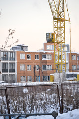 Abandoned construction of a multi-storey building. Tower crane, and a house with broken glass....