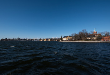 A sunny spring day in Stockholm, view over a pier with boats and birds at the city and old town