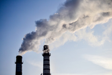 Two pipes. Industrial smoke from a chimney against the sky