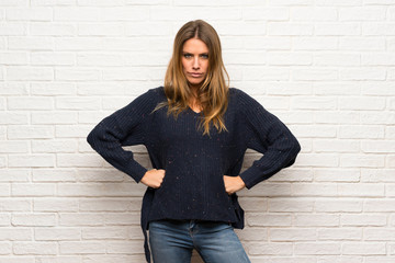 Blonde woman over brick wall angry