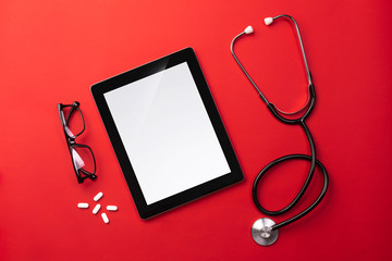 Stethoscope in doctors desk with digital tablet and pills