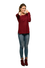 A full-length shot of a Blonde woman making phone gesture and pointing front over isolated white background