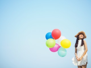 Fototapeta na wymiar Happy Asian woman holding colorful of balloons over blue sky background,copy space.