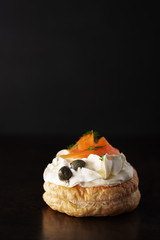 Smoked salmon tartlets snacks with cream cheese on a dark background with copy space.