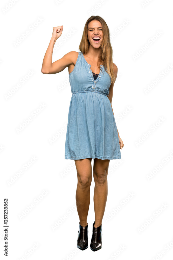 Wall mural a full-length shot of a blonde woman with jean dress celebrating a victory in winner position over i