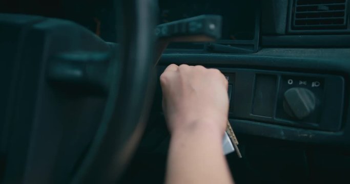 Young woman turning the key in her car ignition