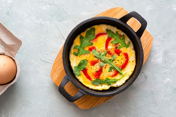 Omelette with fresh pepper and arugula. Frittata in frying pan.