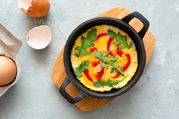 Omelette with fresh pepper and arugula. Frittata in frying pan.