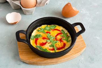 Omelette with fresh pepper and arugula. Frittata in frying pan.