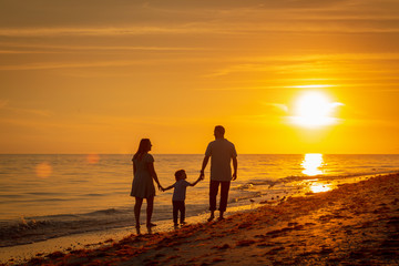 family walking along Florida beach at sunset